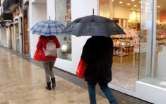 gente paseando con paraguas bajo la lluvia en el centro de denia